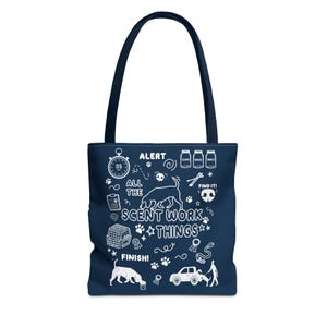 May include: Navy blue tote bag with white illustrations and text. The bag features a dog silhouette, paw prints, and the words "ALERT", "ALL THE SCENT WORK THINGS", and "FINISH!". It has a dark blue handle.
