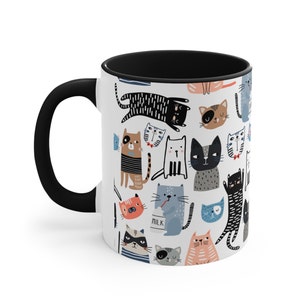 May include: A white ceramic coffee mug with a black handle and black interior. The mug features a repeating pattern of colorful cartoon cats in various poses.