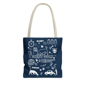 May include: Navy blue tote bag with cream-colored handles. The bag features white illustrations and text, including a stopwatch, paw prints, and the words "ALERT," "ALL THE SCENT WORK THINGS," and "FINISH!"