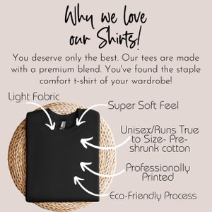 May include: A black t-shirt on a woven surface. Text on the image reads "Why we love our Shirts!" and highlights features like light fabric, super soft feel, and an eco-friendly process. The shirt is described as unisex and pre-shrunk.