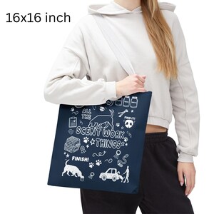 May include: A navy blue tote bag, measuring 16x16 inches, features white illustrations and text related to scent work. The design includes dog silhouettes, paw prints, and the phrases "ALL THE SCENT WORK THINGS" and "FIND IT!".