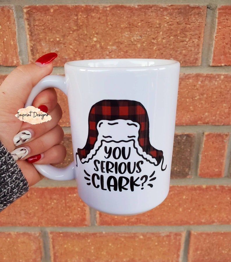 May include: White ceramic mug with a black and red plaid design and the text "You serious Clark?" printed on it.