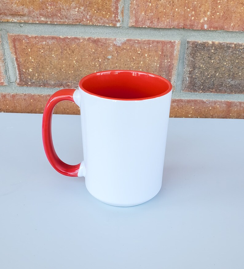 May include: A white ceramic mug with a red rim and handle. The mug is blank and ready to be personalized.
