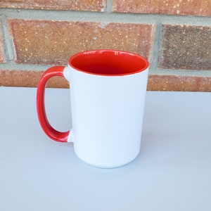 May include: A white ceramic mug with a red rim and handle. The mug is blank and ready to be personalized.