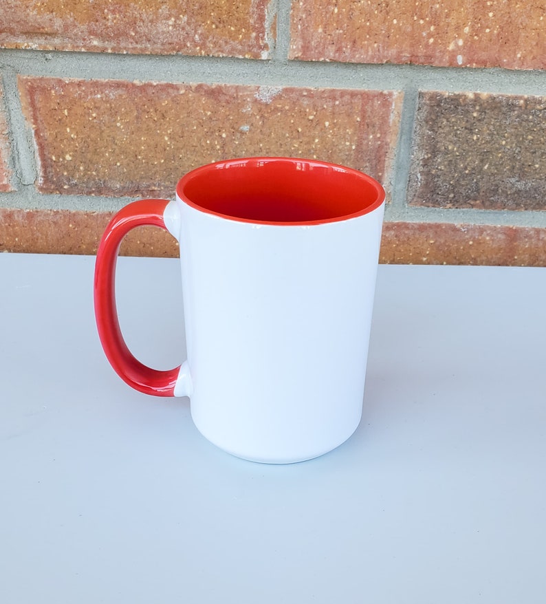 May include: A white ceramic mug with a red rim and handle. The mug is blank and ready to be personalized.