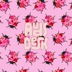 May include: A pink background with a repeating pattern of ladybugs with red and pink hearts. The text "A Day at the Desk" is in the center of the image.