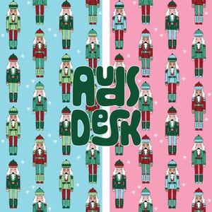 May include: A repeating pattern of nutcracker figures in red, green, and white on light blue and pink backgrounds, featuring small white snowflakes. The dark green text "AUDS DESK" is centered in a bold, rounded, and stylized font over the pattern.