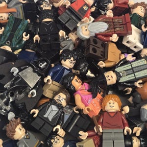 May include: A collection of Lego minifigures, featuring various characters. The figures display a range of colors, including black, brown, red, and blue. Some minifigures have glasses, and others are holding accessories. The overall theme suggests a fantasy or movie-related collection.