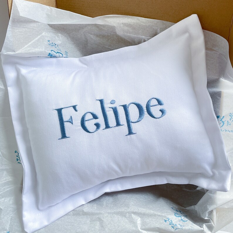 May include: White pillow with blue embroidered text that reads "Felipe".