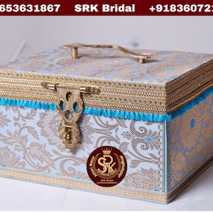 May include: A light blue decorative box with gold trim and a brass handle. The box has a floral pattern and a blue tassel. The box is labeled "SRK Bridal" and has a phone number on the top.