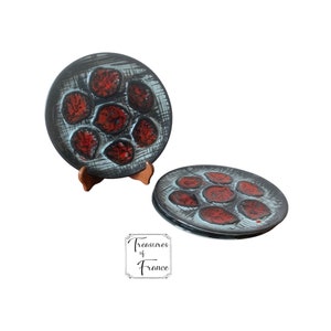 May include: Set of four vintage ceramic plates with a blue and black background and red abstract designs. The plates are stacked on top of each other. The plates are made in France.