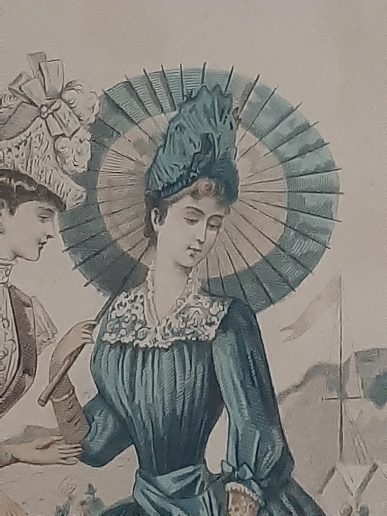 Puede incluir: Una mujer con un vestido azul verdoso con un cuello de encaje blanco y un gran sombrero azul oscuro con una pluma. Lleva un paraguas con una cubierta a rayas blancas y verdes.