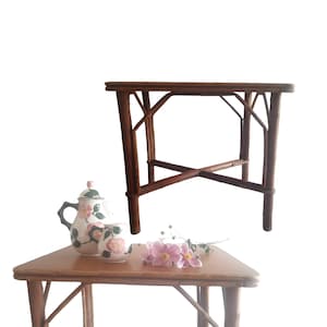 Peut inclure: Deux tables en bois avec un plateau triangulaire. La table du bas a une théière et deux tasses avec des motifs floraux. La table du haut est une table carrée avec un design simple.