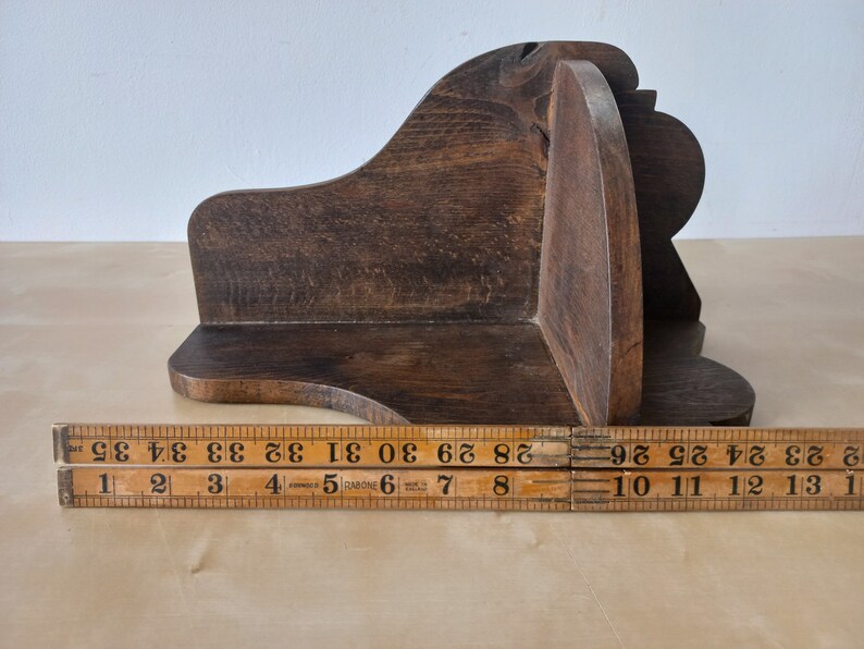 K&ouml;nnte beinhalten: Ein dunkelbraunes Eckregal aus Holz mit einem geschwungenen Design. Das Regal ist etwa 25 cm breit.