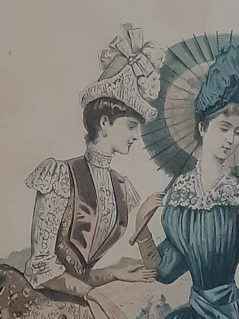 Puede incluir: Dos mujeres con ropa vintage, una lleva un sombrero blanco con un lazo y la otra un sombrero azul con una sombrilla. La mujer con la sombrilla la sostiene sobre su cabeza.