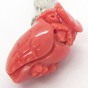 May include: A carved coral owl pendant in a bright pink color. The owl is detailed with carved feathers and eyes.