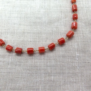 May include: A necklace made of red coral beads strung on a gold chain.