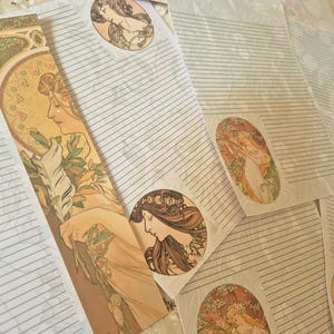 Può includere: Set di carta da lettere con illustrazioni in stile Art Nouveau raffiguranti donne di profilo e motivi floreali. I fogli sono a righe in tenui tonalità crema e pastello, caratterizzati da bordi decorativi e vignette circolari.