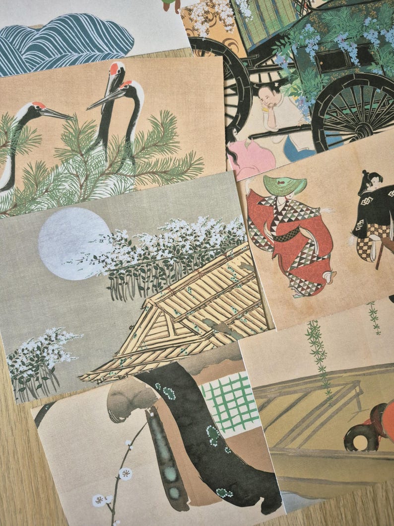 K&ouml;nnte beinhalten: Eine Sammlung rechteckiger Postkarten mit traditionellen japanischen Kunstdrucken. Die Bilder zeigen verschiedene Szenen, darunter Mandschurenkraniche, eine Pferdekutsche, einen Vollmond &uuml;ber einem Holzbau und Figuren in gemusterten Gew&auml;ndern.