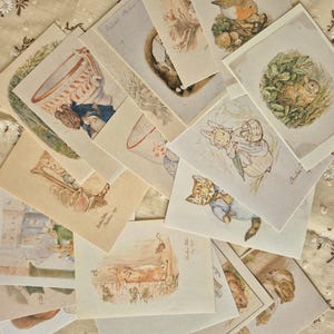 Może przedstawiać: Kolekcja prostokątnych kartek okolicznościowych z akwarelowymi ilustracjami w stylu vintage przedstawiającymi antropomorficzne zwierzęta, w tym króliki, kotka w niebieskiej kurtce i ptaka, ułożone w wachlarz.