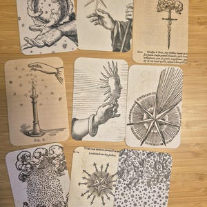 Peut inclure: Un ensemble de huit cartes rectangulaires présentant des illustrations vintage en noir et blanc. Les motifs incluent des corps célestes, des mains, une bougie, une épée et des étoiles, avec du texte imprimé en latin et en anglais sur certaines.