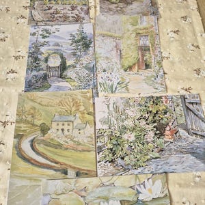 Può includere: Una collezione di sette cartoline rettangolari con dipinti paesaggistici ad acquerello. Le scene raffigurano vari giardini, un cottage in pietra in una valle, un muro di pietra con piante rampicanti e uno stagno con ninfee bianche.