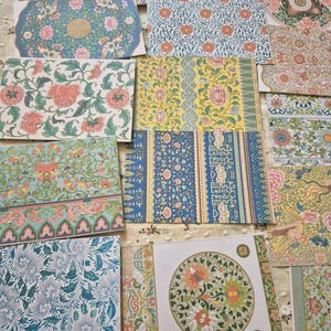 Pode incluir: Uma coleção de cartões de papel retangulares com diversos padrões florais e geométricos em cores vibrantes, incluindo azul, verde, amarelo e rosa. Os designs incluem motivos botânicos intrincados, medalhões circulares e bordas repetitivas.