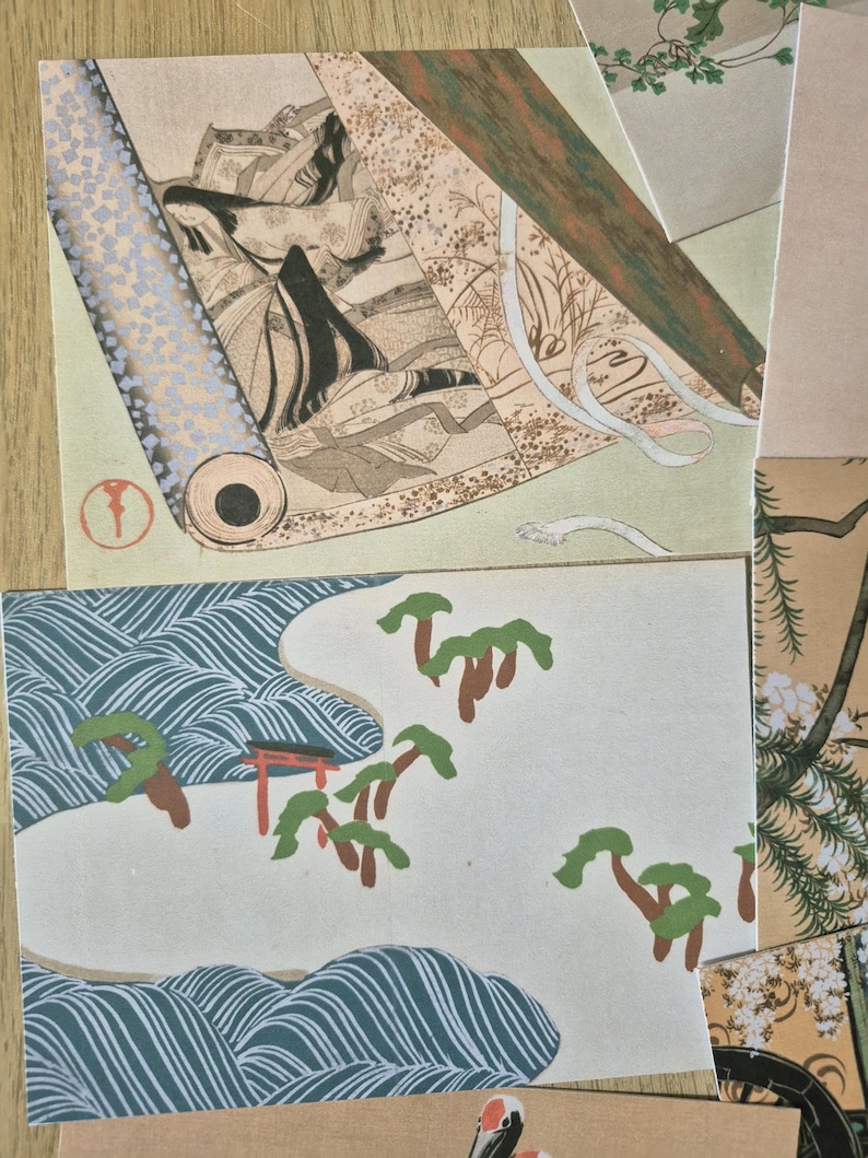 K&ouml;nnte beinhalten: Eine Sammlung rechteckiger Papierdrucke mit traditioneller japanischer Kunst. Ein Druck zeigt eine Figur mit langem schwarzem Haar in einer rollenartigen Komposition, w&auml;hrend ein anderer eine Landschaft mit stilisierten blauen Wellen, gr&uuml;nen B&auml;umen und einem roten Torii-Tor darstellt.