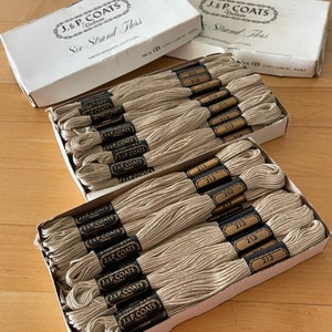 May include: A box of J & P Coats Deluxe Six Strand Floss in a beige color. The box is open and the floss is visible. The floss is labeled with the number 213.