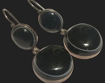 May include: A pair of silver earrings with black onyx stones. The earrings have a double-drop design with two round stones on each earring.