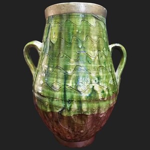 May include: A large green ceramic pitcher with two handles. The pitcher has a wavy pattern and a brown base.