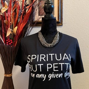 May include: Black t-shirt with white text that reads "Spiritual but Petty on any given day".