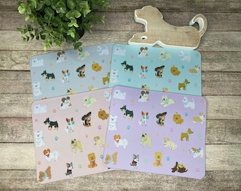Puede incluir: Cuatro alfombrillas de ratón diferentes con un patrón repetido de perros de dibujos animados que llevan bandanas. Las alfombrillas de ratón son en tonos de rosa, azul y blanco.