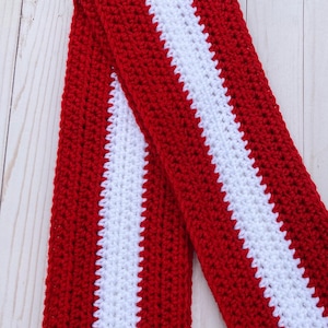 Red and white striped crocheted scarf folded in half and laid at an angle.  Stripes run lengthwise on the scarf.  There are two red stripes on the outside lengths of the scarf, and the center stripe is white.