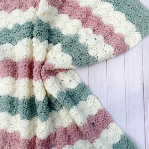 May include: A crocheted baby blanket with a wavy pattern in shades of pink, white, and green.