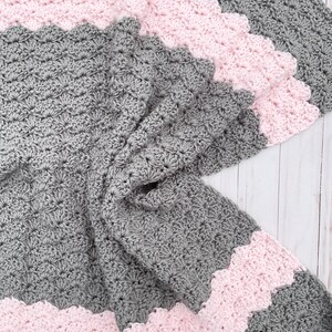 May include: A gray and pink crocheted baby blanket with a scalloped edge.