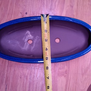 May include: A blue and brown oval ceramic planter with drainage holes. The planter is 7 inches long.