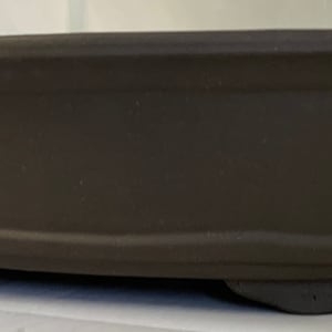May include: A brown oval ceramic bonsai pot with a slightly flared rim and three small feet on the bottom.
