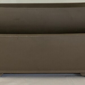 May include: Two brown rectangular ceramic bonsai pots, one stacked on top of the other. The top pot is slightly smaller than the bottom pot.