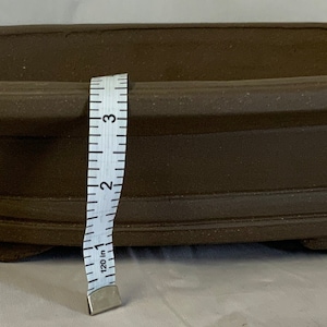 May include: A brown oval ceramic bonsai pot with a textured surface and a raised rim. The pot is approximately 12 inches long and 6 inches wide.