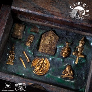 Könnte beinhalten: Eine Holzkiste mit dunkelgrünem Innenraum, die verschiedene kleine, goldfarbene religiöse Artefakte enthält. Die Artefakte umfassen kleine Statuen, Amulette und eine runde Münze. Die Kiste ist geöffnet und zeigt den Inhalt, mit antiker Ästhetik.