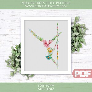 Puede incluir: Un patr&oacute;n de punto de cruz con una persona haciendo telas a&eacute;reas, con un dise&ntilde;o floral en tonos de rosa, azul, amarillo y verde. El patr&oacute;n est&aacute; en un marco blanco con el texto "MODERN CROSS STITCH PATTERNS WWW.STITCHAREA.ETSY.COM" en la parte superior y "FOR HAPPY STITCHING!" en la parte inferior. La imagen tambi&eacute;n incluye la palabra "PDF" en un cuadro rojo.