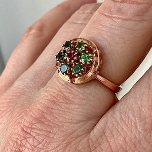 Peut inclure: Une bague en or avec un groupe de pierres précieuses rouges et vertes serties dans un motif circulaire.