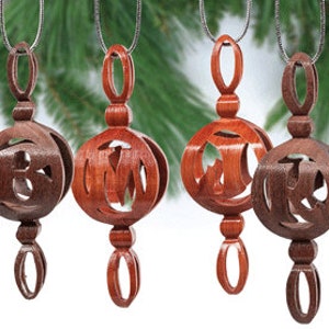 May include: Four wooden Christmas ornaments with a cutout design. The ornaments are in shades of brown and red.