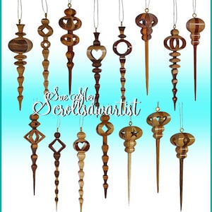 May include: A collection of handcrafted wooden ornaments in various shapes, including teardrops, stars, and geometric designs. The ornaments are made from different wood tones and feature intricate cut-out patterns. The text "Sue of Men Scrollsdwartist" is visible.