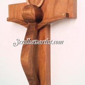 May include: A wooden crucifix with a stylised figure of Jesus Christ. The figure is made of wood and has a halo above its head. The cross is made of wood and has a simple design.