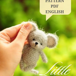 Op de afbeelding: Een kleine, pluizige, lichtgrijze gehaakte muis met ronde oren, zwarte ogen en een zwarte neus. Een tekstballon boven de muis bevat de tekst CROCHET PATTERN PDF ENGLISH, en de tekst Little MOUSE staat rechtsonder in de afbeelding.
