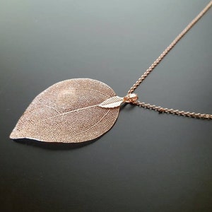 May include: A delicate rose gold necklace with a leaf pendant. The leaf is made of a thin metal and has a detailed vein pattern.