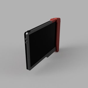 Op de afbeelding: Een zwart handheld-apparaat met een rode zijpaneel en een zwart scherm. Het apparaat heeft twee kleine zwarte knoppen aan de zijkant.