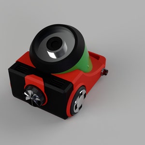 Puede incluir: Un robot de juguete rojo y negro con una parte superior verde y plateada. El robot tiene una rueda grande en la parte superior y una rueda m&aacute;s peque&ntilde;a en el lateral.